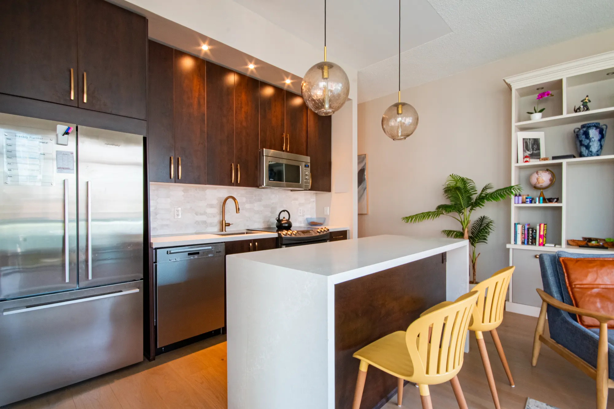 Modern condo kitchen with waterfall island, pendant lights and dark cabinetry