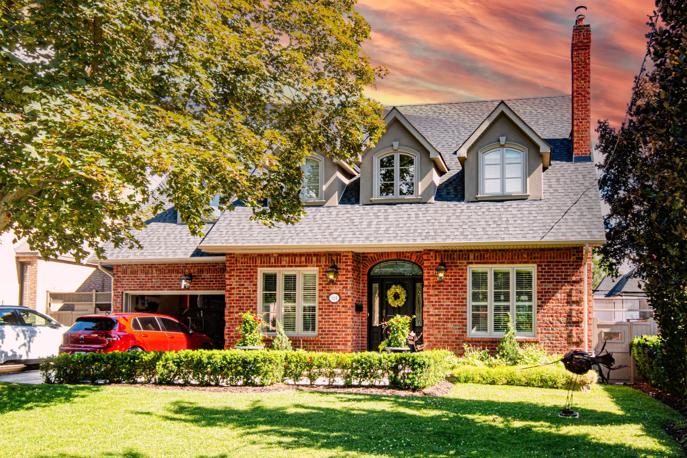 Front exterior of a red-brick two-storey home with manicured gardens